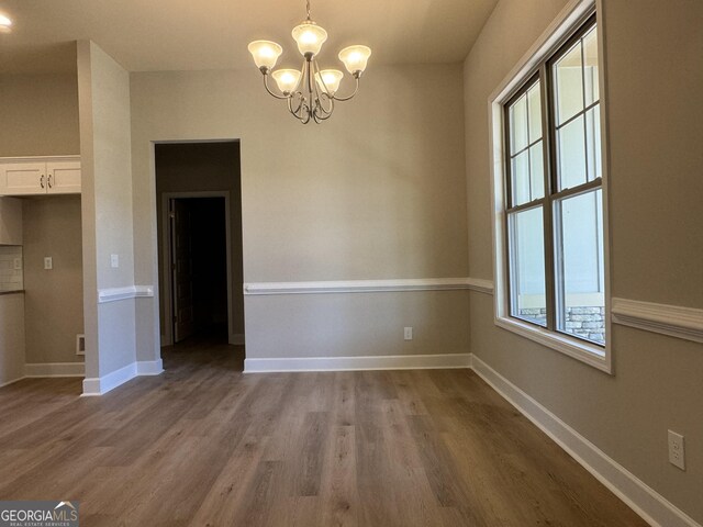 unfurnished dining area with a notable chandelier and light hardwood / wood-style floors