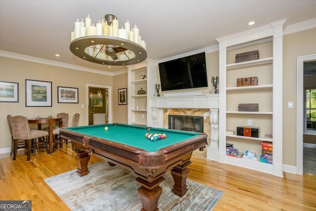 recreation room with built in shelves, crown molding, and light hardwood / wood-style flooring