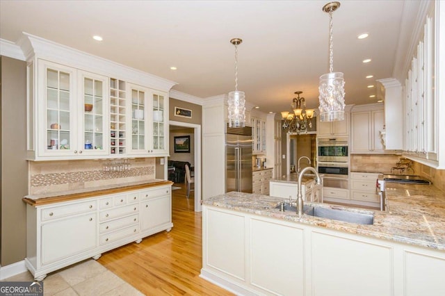 kitchen featuring kitchen peninsula, hanging light fixtures, backsplash, appliances with stainless steel finishes, and sink