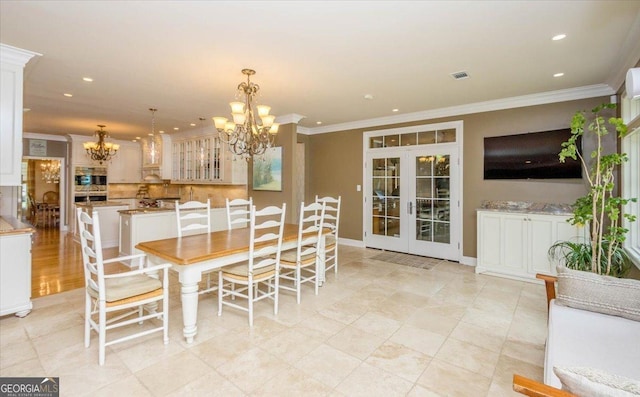 dining area with ornamental molding, french doors, and an inviting chandelier