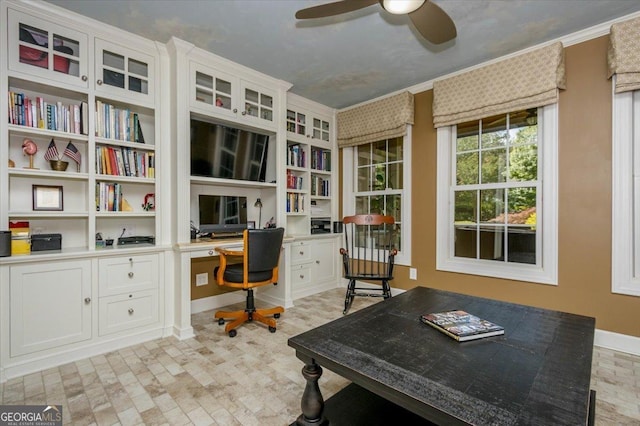 office with built in desk, ceiling fan, and ornamental molding