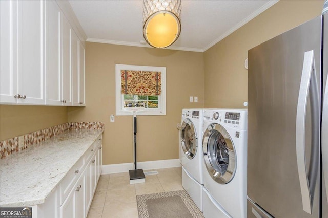 laundry room with cabinets, crown molding, washing machine and clothes dryer, and light tile patterned floors