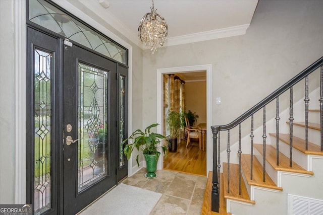 foyer with ornamental molding and a chandelier