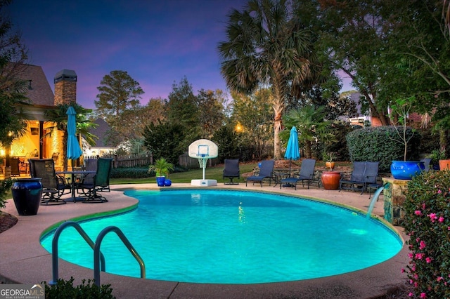 pool at dusk featuring a patio