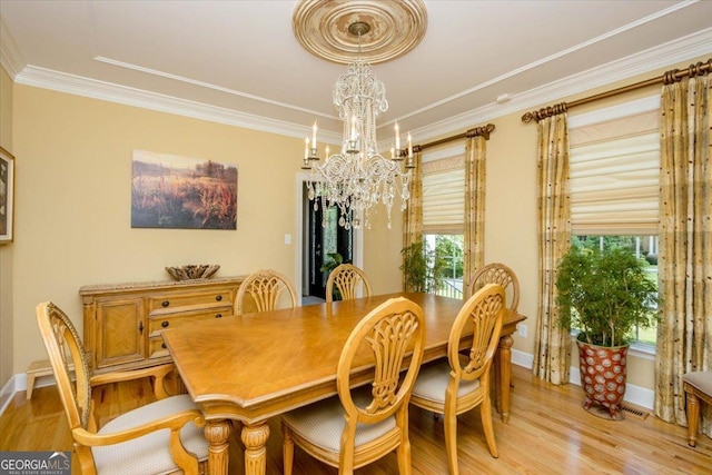 dining area with ornamental molding, a wealth of natural light, a notable chandelier, and light hardwood / wood-style flooring