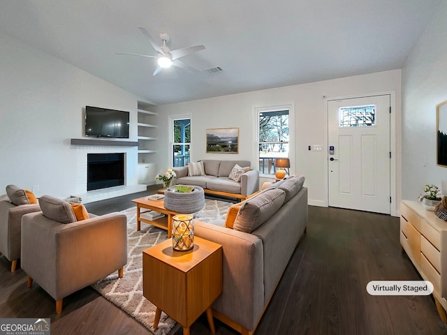 living room with a brick fireplace, dark hardwood / wood-style flooring, ceiling fan, and vaulted ceiling