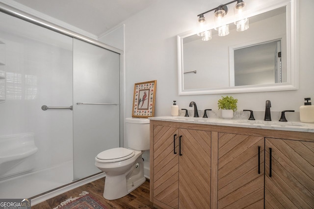 bathroom featuring toilet, hardwood / wood-style flooring, a shower with door, and vanity