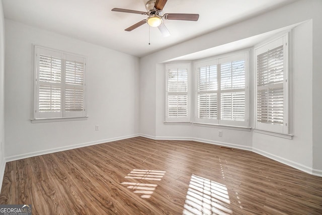 empty room with ceiling fan and dark hardwood / wood-style floors