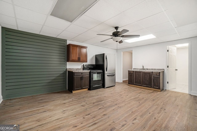 kitchen featuring a paneled ceiling, sink, stainless steel fridge, black electric range, and light wood-type flooring