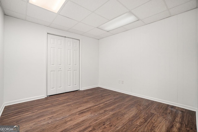 unfurnished bedroom featuring a closet, dark hardwood / wood-style flooring, and a drop ceiling