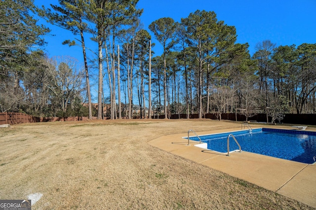 view of swimming pool featuring a lawn and a diving board