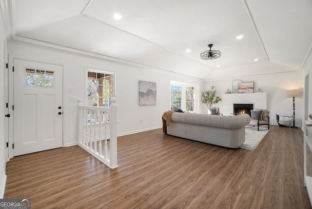 living room with crown molding, hardwood / wood-style floors, a brick fireplace, and lofted ceiling