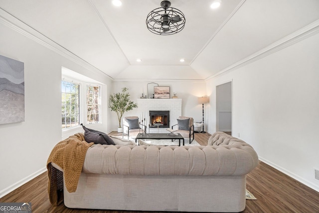 living room featuring a fireplace, dark hardwood / wood-style floors, lofted ceiling, and ornamental molding