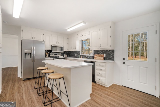 kitchen with a kitchen island, white cabinetry, a breakfast bar, and stainless steel appliances