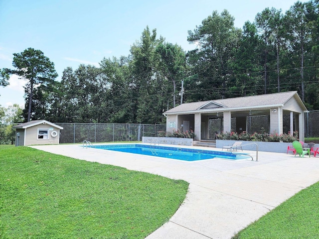 view of pool with a lawn, a patio area, and an outdoor structure