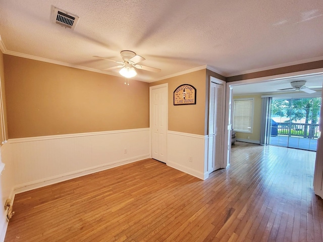 empty room with a textured ceiling, hardwood / wood-style floors, ceiling fan, and ornamental molding