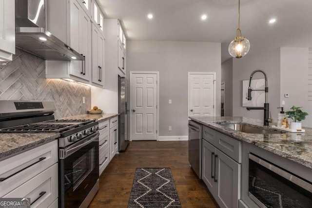 kitchen featuring sink, stainless steel appliances, wall chimney range hood, and white cabinetry