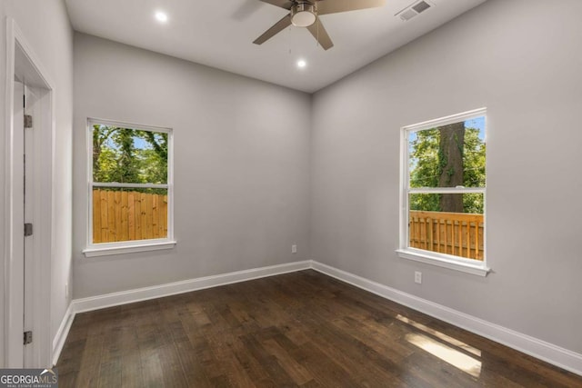 unfurnished room featuring ceiling fan, dark wood-type flooring, and a healthy amount of sunlight