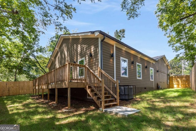 rear view of house featuring cooling unit, a lawn, and a wooden deck