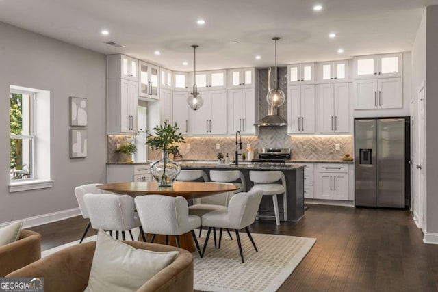 kitchen featuring decorative light fixtures, a center island with sink, appliances with stainless steel finishes, and white cabinetry