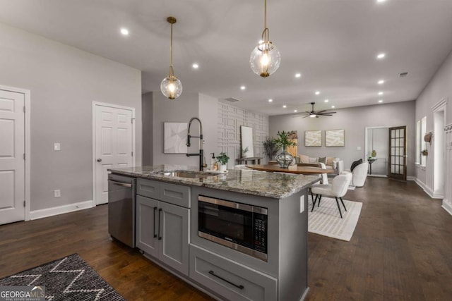 kitchen with appliances with stainless steel finishes, gray cabinetry, an island with sink, ceiling fan, and pendant lighting