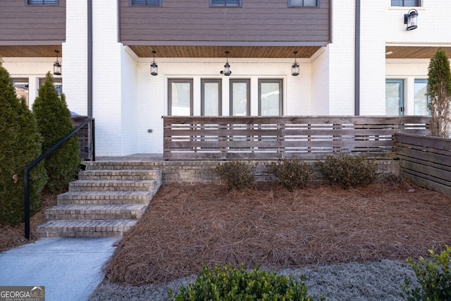 doorway to property featuring a porch and brick siding