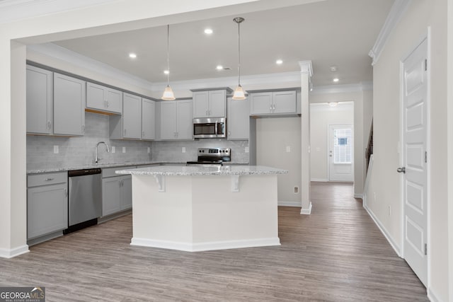 kitchen featuring decorative light fixtures, a center island, decorative backsplash, light stone countertops, and appliances with stainless steel finishes