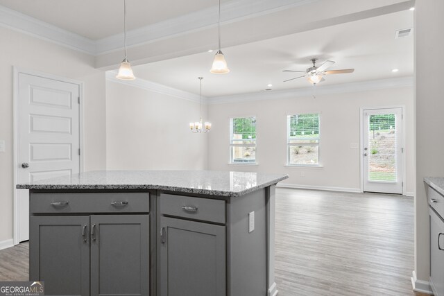 kitchen with hanging light fixtures, a center island, crown molding, and ceiling fan with notable chandelier