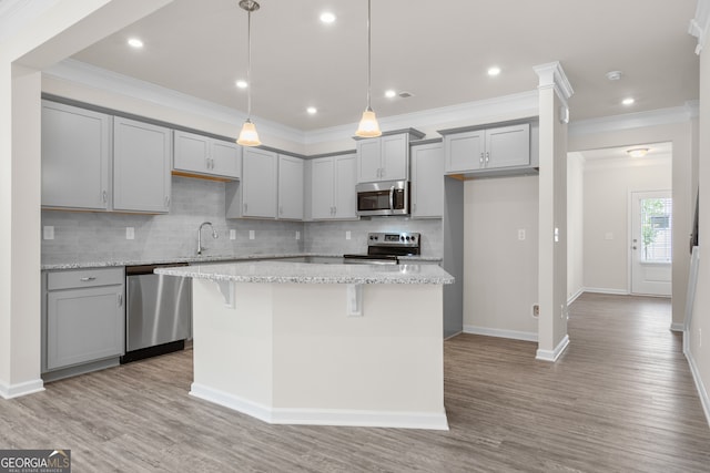 kitchen with stainless steel appliances, a kitchen island, backsplash, and light stone countertops