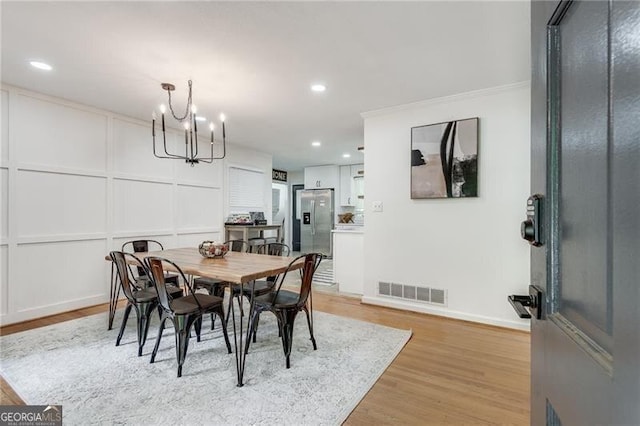 dining space with an inviting chandelier, light hardwood / wood-style floors, and crown molding