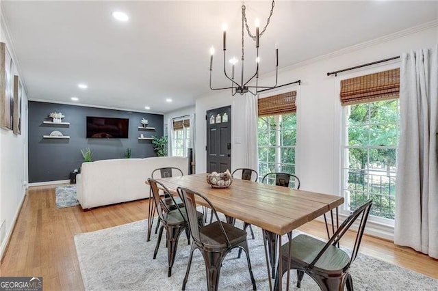 dining space with an inviting chandelier, ornamental molding, and light hardwood / wood-style floors