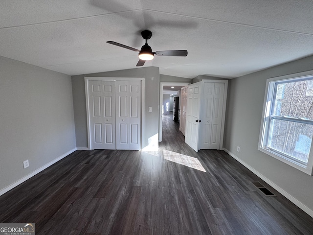 unfurnished bedroom with lofted ceiling, dark wood-type flooring, a textured ceiling, and ceiling fan