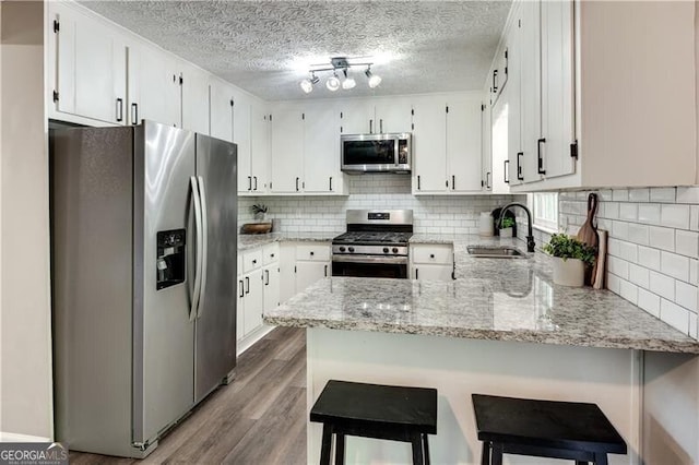 kitchen with sink, stainless steel appliances, white cabinets, and kitchen peninsula