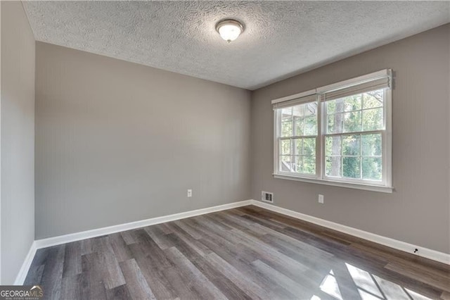 spare room featuring a textured ceiling and hardwood / wood-style flooring