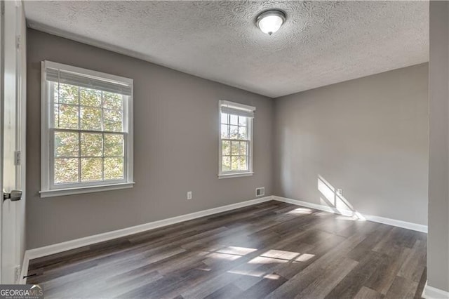 empty room featuring a textured ceiling and dark hardwood / wood-style floors