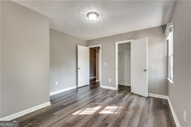 unfurnished bedroom featuring a textured ceiling, a closet, and dark hardwood / wood-style flooring