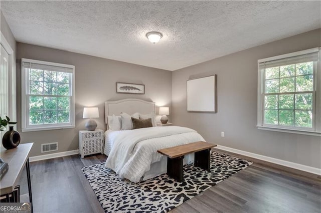 bedroom with a textured ceiling, multiple windows, and dark hardwood / wood-style floors