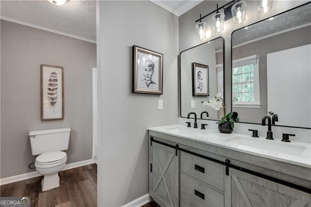 bathroom featuring toilet, a textured ceiling, hardwood / wood-style floors, ornamental molding, and vanity