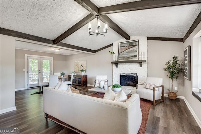 living room with a textured ceiling, dark wood-type flooring, a stone fireplace, and lofted ceiling with beams