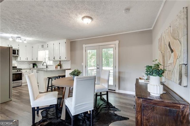 dining room featuring crown molding, french doors, dark hardwood / wood-style floors, a textured ceiling, and sink