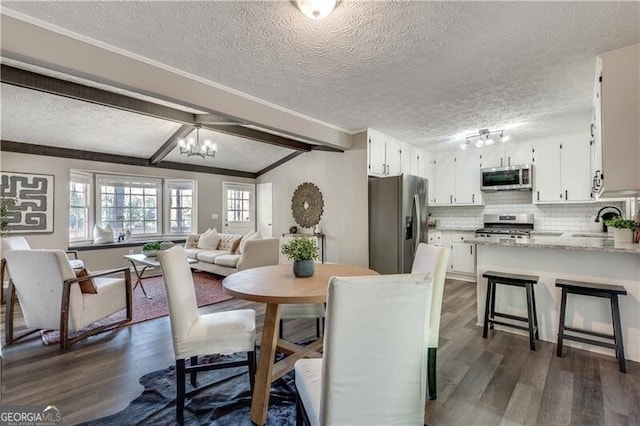 dining space featuring dark wood-type flooring, a textured ceiling, sink, a notable chandelier, and vaulted ceiling with beams