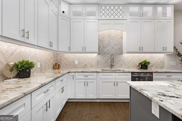 kitchen featuring light stone counters, dishwasher, tasteful backsplash, white cabinetry, and sink