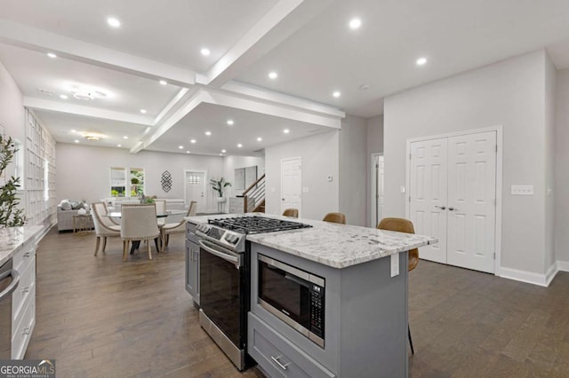 kitchen with dark wood-type flooring, a center island, stainless steel appliances, gray cabinets, and a breakfast bar area