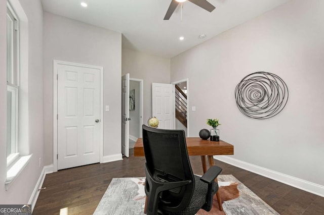 office featuring a towering ceiling, dark wood-type flooring, and ceiling fan