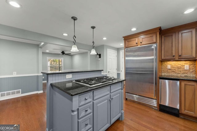 kitchen featuring stainless steel appliances, dark stone countertops, ceiling fan, hanging light fixtures, and gray cabinetry