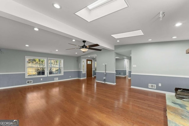 unfurnished living room with ceiling fan, lofted ceiling with skylight, and wood-type flooring