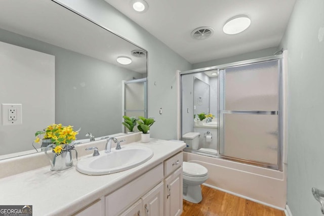 full bathroom featuring toilet, combined bath / shower with glass door, vanity, and hardwood / wood-style floors