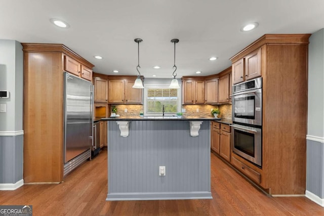 kitchen featuring decorative light fixtures, a center island, light wood-type flooring, and appliances with stainless steel finishes