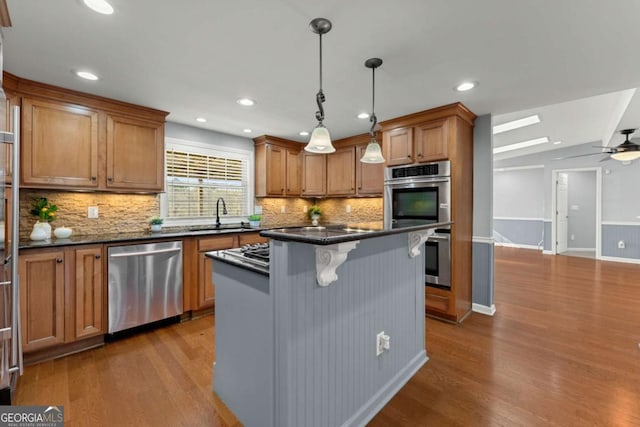 kitchen with stainless steel appliances, a center island, pendant lighting, hardwood / wood-style flooring, and sink