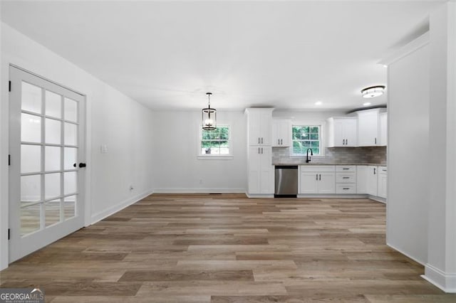 kitchen featuring dishwasher, white cabinets, decorative light fixtures, backsplash, and sink